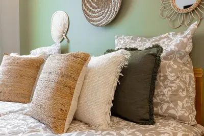 a group of pillows on a bed with a wall at L'atelier des Artistes -Écrin de sérénité au coeur de Cannes - Balcon - Clim - Wifi in Cannes