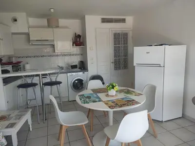 a kitchen with a table and chairs and a white refrigerator at LE PALAZZIO - Proximité immédiate Palais des festival ,Vieux Port et plages - Garage in Cannes