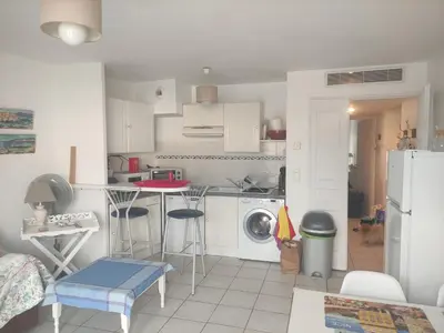 a small kitchen with a table and a refrigerator at LE PALAZZIO - Proximité immédiate Palais des festival ,Vieux Port et plages - Garage in Cannes