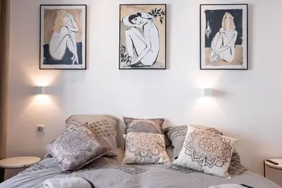 a bedroom with four pictures on the wall above a bed at Luxury Apt With Balcony On Famous Rue D'antibes! - Kiss Apartment by Halldis in Cannes