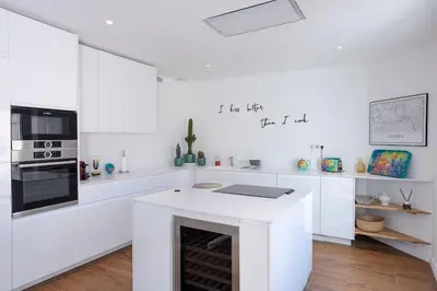 a white kitchen with white cabinets and a fireplace at Luxury Apt With Balcony On Famous Rue D'antibes! - Kiss Apartment by Halldis in Cannes