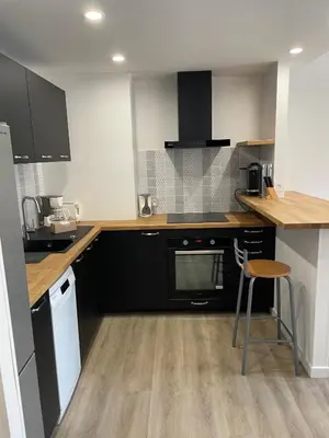 a kitchen with black cabinets and a wooden counter top at Modern and pleasant apartment in the heart of the city in Cannes