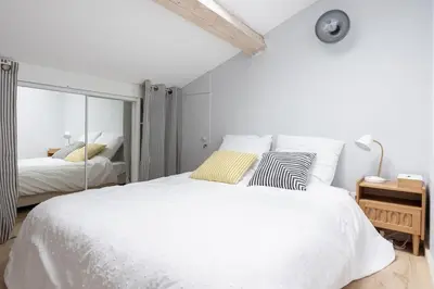 a white bedroom with a large bed and a mirror at Appartement sous les toits 5 min du palais à pied in Cannes