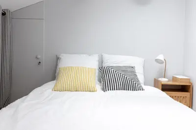 a bedroom with a white bed with two pillows at Appartement sous les toits 5 min du palais à pied in Cannes