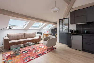 a living room with a couch and a table at Appartement sous les toits 5 min du palais à pied in Cannes