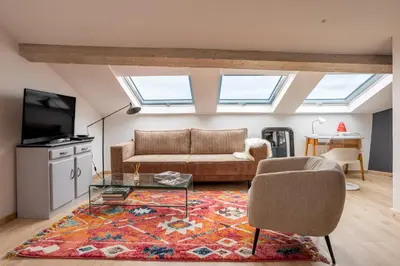 a living room with a couch and a table at Appartement sous les toits 5 min du palais à pied in Cannes
