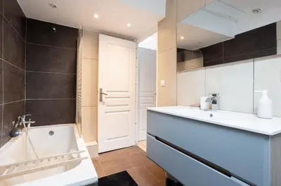 a bathroom with a tub and a sink at Appartement sous les toits 5 min du palais à pied in Cannes