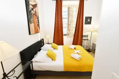 a bedroom with a yellow and white bed with towels on it at Tou'Can YourHostHelper in Cannes