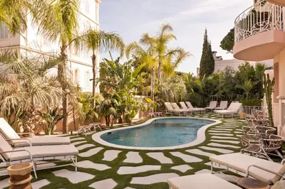 a resort pool with lounge chairs and palm trees at Maison Carla Rosa Cannes in Cannes