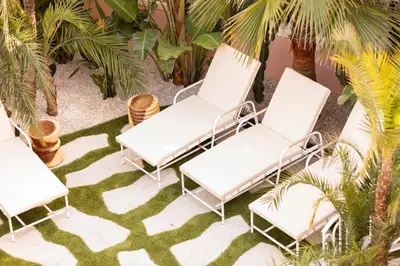 a group of white chairs on a lawn with palm trees at Maison Carla Rosa Cannes in Cannes
