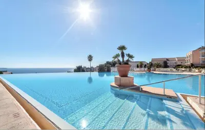 a large swimming pool with blue water and palm trees at Appt Vue Mer Exceptionnelle sur baie de Cannes in Cannes