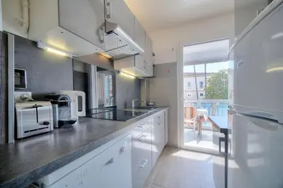 a kitchen with white cabinets and a large window at Le Jak - 2 Pièces - Loggia - VCA in Cannes