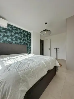 a bedroom with a large bed with a blue wall at AGENCIA appartement 2 Pièces lumineux terrasse in Cannes