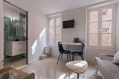 a white living room with two chairs and a table at Maison Denise - Suquet vue sur la Cathédrale in Cannes