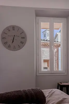 a clock on a wall next to a window at Maison Denise - Suquet vue sur la Cathédrale in Cannes