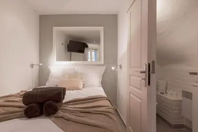 a white bedroom with a bed with a mirror at Maison Denise - Suquet vue sur la Cathédrale in Cannes