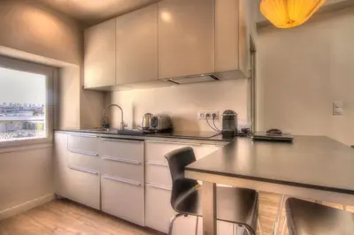 a kitchen with white cabinets and a table and chairs at 9E - Appartement 1 chambre in Cannes