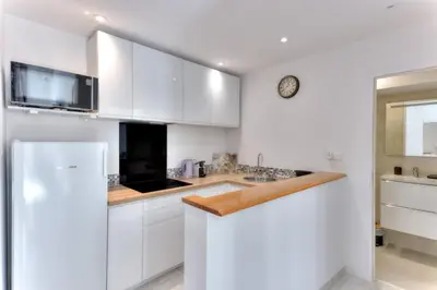 a kitchen with white cabinets and a white refrigerator at LE FELIX au cœur du centre-ville, emplacement idéal pour loisirs ou congrès in Cannes