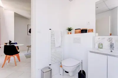 a white bathroom with a toilet and a table at LA PANTHERE studio design central et calme, idéal pour un séjour en couple ou congrès in Cannes