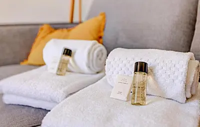 a bed with towels and a bottle of perfume at LA PANTHERE studio design central et calme, idéal pour un séjour en couple ou congrès in Cannes