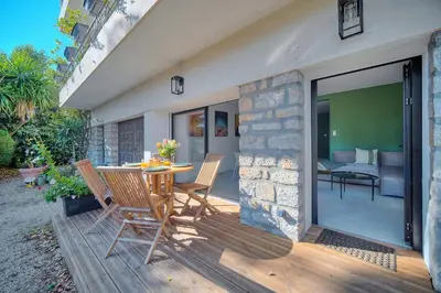 a patio with a table and chairs on a wooden deck at Beau 2 chambres TERRASSE, JARDIN, Picaud- Proche Plages MIDI A2B241 in Cannes