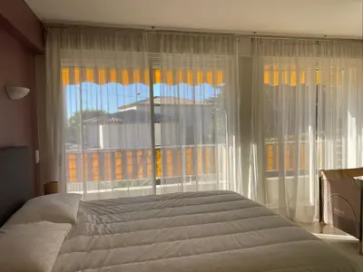 a bedroom with a bed and a large window at C012-Appartement confortable avec piscine, tennis et grand parc in Cannes