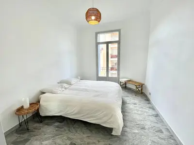 a white bedroom with a large bed and a window at T2 Cannes centre - Appartement cosy proche Palais in Cannes
