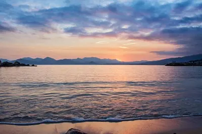 a sunset over a body of water with mountains at Cannes Croisette Rue Meynadier Palais 1 mn Modern 1 BR by Olam Properties in Cannes
