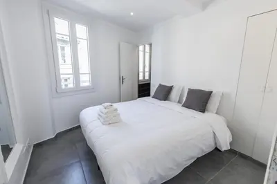 a white bedroom with a large white bed and two windows at Cannes Croisette Rue Meynadier Palais 1 mn Modern 1 BR by Olam Properties in Cannes