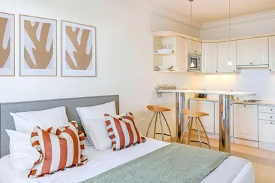 a bedroom with a bed and a kitchen at Buckingham & Lloyds - Cannes in Cannes