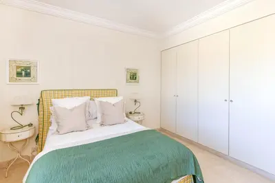 a white bedroom with a bed with a green blanket at Buckingham & Lloyds - Cannes in Cannes