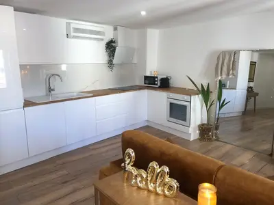 a kitchen with white cabinets and a couch in a room at Cocon Forville - Palais des Festivals, Plages, clim, marché provençal, Vieux Port et Suquet in Cannes