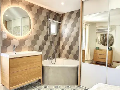 a bathroom with a tub and a sink and a mirror at Cocon Forville - Palais des Festivals, Plages, clim, marché provençal, Vieux Port et Suquet in Cannes