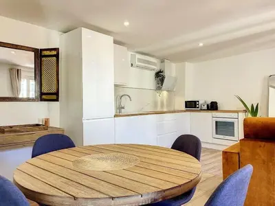 a kitchen with a wooden table and blue chairs at Cocon Forville - Palais des Festivals, Plages, clim, marché provençal, Vieux Port et Suquet in Cannes