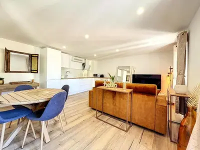 a kitchen and living room with a table and blue chairs at Cocon Forville - Palais des Festivals, Plages, clim, marché provençal, Vieux Port et Suquet in Cannes