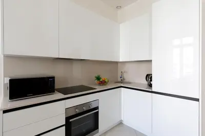 a kitchen with white cabinets and a microwave at Gazagnaire YourHostHelper in Cannes