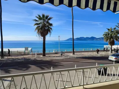 a view of a beach with palm trees and the ocean at Le Madrigal by Halldis in Cannes