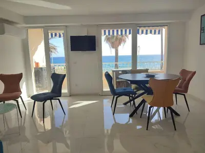 a dining room with a table and chairs and the ocean at Le Madrigal by Halldis in Cannes