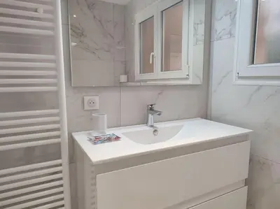 a white bathroom with a sink and a mirror at Le Madrigal by Halldis in Cannes