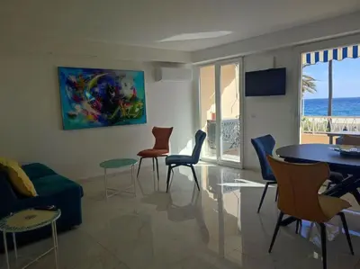 a living room with a table and chairs and the ocean at Le Madrigal by Halldis in Cannes
