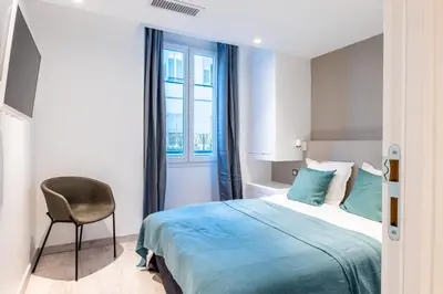 a bedroom with a bed and a chair and a window at 1-Br apartment close to the beaches in Cannes