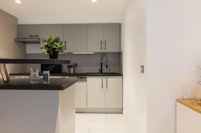 a kitchen with white cabinets and black counter tops at 1-Br apartment close to the beaches in Cannes