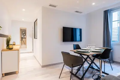 a dining room with a table and chairs and a tv at 1-Br apartment close to the beaches in Cannes