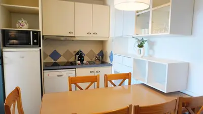 a kitchen with white cabinets and a wooden table at Appartement 616, 5 personnes belle vue Mer By Palmazur Vacances in Cannes