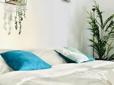a bed with blue and white pillows and a plant at Le Cocon - 2 pièces centre Cannes - Terrasse in Cannes