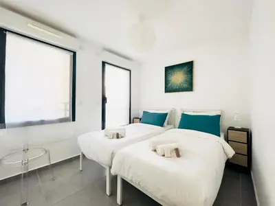 two beds in a room with white walls and blue pillows at Le Cocon - 2 pièces centre Cannes - Terrasse in Cannes