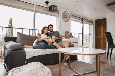a man and woman sitting on a couch in a living room at Piscine-Jacuzzi-Sauna -Videoprojecteur Perle Rare in Mougins