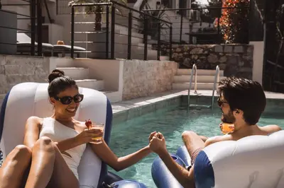 two people sitting in a pool with drinks at Piscine-Jacuzzi-Sauna -Videoprojecteur Perle Rare in Mougins