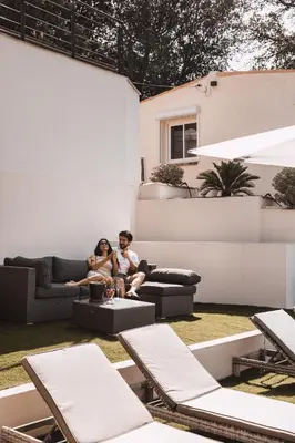 a man and woman sitting on a couch in a yard at Piscine-Jacuzzi-Sauna -Videoprojecteur Perle Rare in Mougins