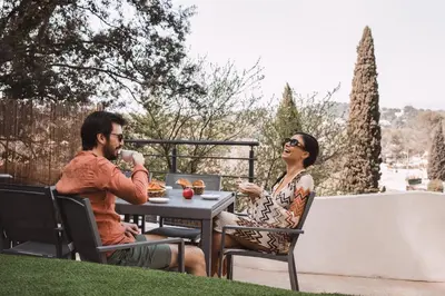 a man and woman sitting at a table drinking coffee at Piscine-Jacuzzi-Sauna -Videoprojecteur Perle Rare in Mougins